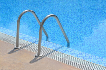 Outdoor swimming pool with ladder and handrails on sunny day