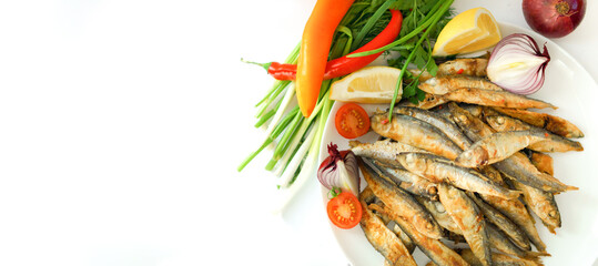 Fried small herring is laid out on a white plate.