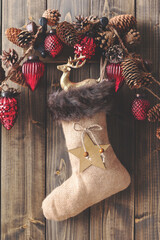 Christmas sock with christmas decorations on wooden wall.