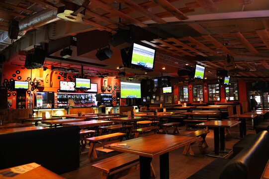 Interior of an empty sport pub, wooden tables, screens, bar counter with drinks on shelves. Kyiv, Ukraine
