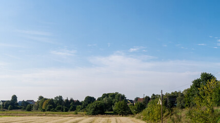 Fototapeta na wymiar Pojedyncze chmury w krajobrazie wiejskim pośrodku samotnego pola, pora letnia Opolszczyzna, błękitne barwy