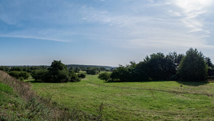 Fototapeta na wymiar Pojedyncze chmury na niebie w krajobrazie wiejskim pośrodku obszarów wiejskich i pola, pora letnia Opolszczyzna, błękitne barwy