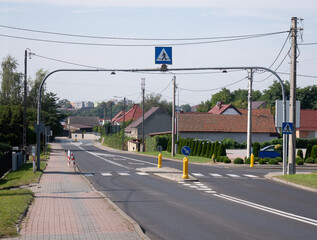 Fototapeta na wymiar Przejście dla pieszych z sygnalizacją świetlną w podmiejskim rejonie zachodniej Polski o letniej porze