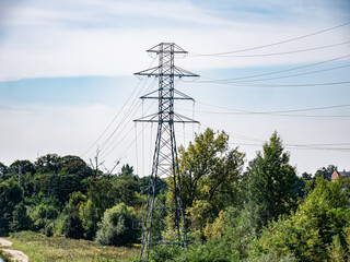 linia elektryczna idąca drogą polną, błękit nieba lekko pochmurna pogoda w tle, pora letnia	