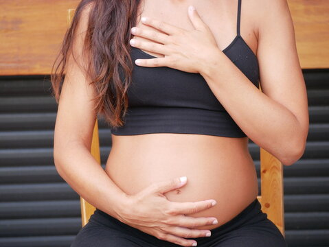Midsection of Pregnant Woman Holding Her Belly and doing yoga