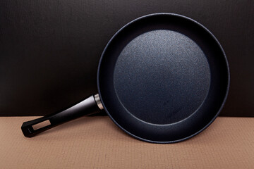 New black granite pan on gray background.