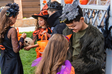 Smiling asian boy in costume talking to friend during halloween party in backyard