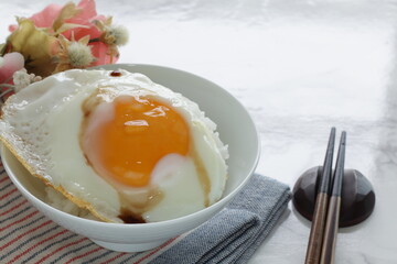 Sunny side up fried egg on rice with soy sauce for Asian breakfast food