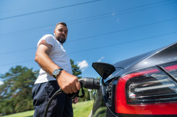 Naklejka premium Caucasian man connect charger to electric car. 