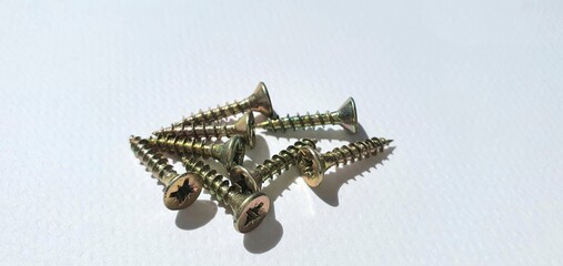 Small screws close up. New gold screws on a white background. Tools for repair.