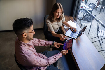 Fototapeta premium Portrait of woman and man pointing to tablet relaxing in coffee bar.