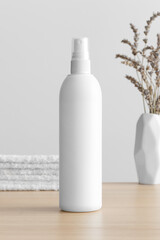 White cosmetic spray bottle mockup with a lavender and towels on the wooden table.
