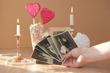 stack of vintage photos in female hand, romantic still life in love style, in glass vase red hearts...