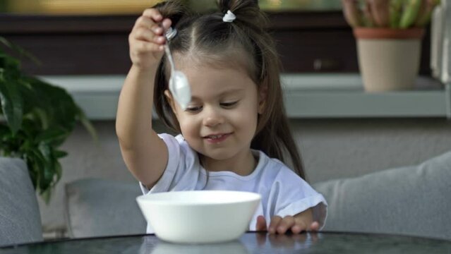 Cute little girl 2 years old does not want to eat porridge. Baby food concept.