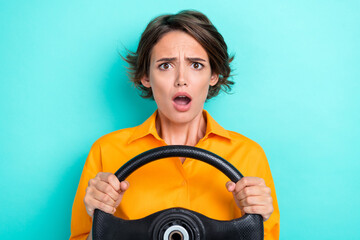 Photo of young pretty attractive gorgeous nice woman wear yellow shirt hold steering wheels open mouth scared isolated on cyan color background