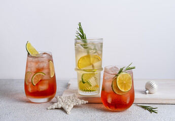 Three colorful Christmas cocktails in glasses on white table. Assortment of fresh holiday drinks. Strawberry Mojito, orange punch cocktail, tropical mule.
