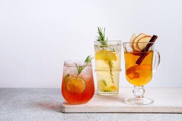 Watermelon and lime punch, tropical mule, orange gin tonic. Colorful Christmas cocktails in glasses on white table.  Fresh holiday drinks.