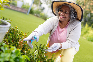 Happy senior african american women wearing hat in the garden