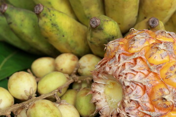 Ripe banana and pineapple on greenish leaves
