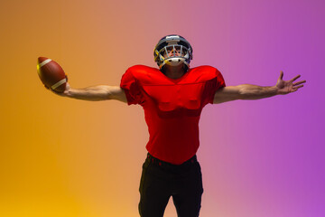 Caucasian male american football player holding ball with neon yellow and purple lighting