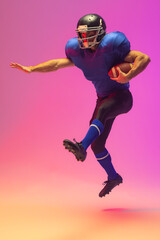 Fototapeta na wymiar Caucasian male american football player holding ball with neon pink lighting