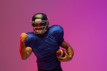 Caucasian male american football player holding ball with neon pink lighting