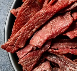 Closeup of beef jerky pieces on black plate