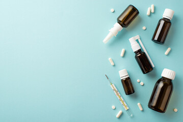 Naklejka premium Illness concept. Top view photo of medicines syrup and spray brown bottles pills capsules and thermometer on isolated pastel blue background with empty space