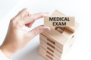 Medical exam is written on wooden cube in the doctor's hand on a light background, medical concept