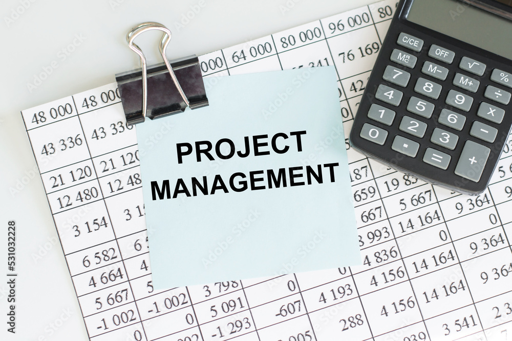 Aufkleber project management text on paper clipboard with magnifier and keyboard on a wooden background