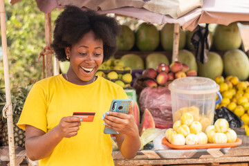african lady using her credit card and phone in a market