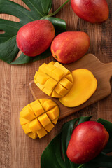 Fresh mango fruit with leaves over dark wooden table background.