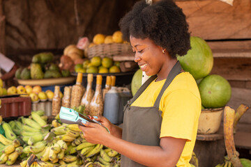 african market woman using a pos device and a credit card