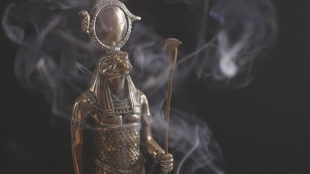 golden statue of the Egyptian god Ra in smoke on a black background