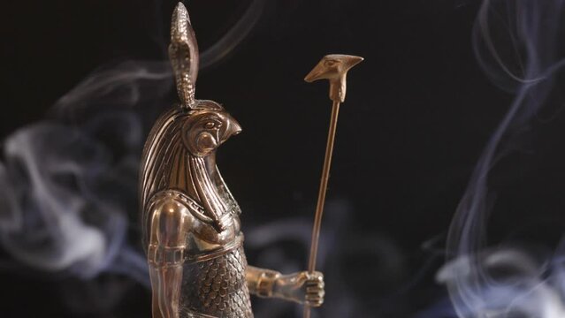 golden statue of the Egyptian god Ra in smoke on a black background