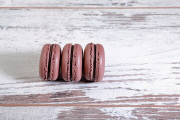 Cocoa macarons on wooden background.