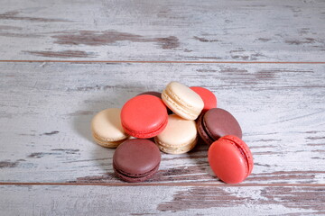 Cocoa, strawberry and almond macarons on wooden background.