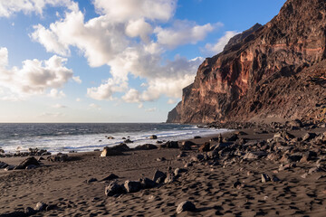 Scenic view during sunset on the volcanic sand beach Playa del Ingles in Valle Gran Rey, La Gomera, Canary Islands, Spain, Europe. Massive cliffs of the La Mercia range. Calm atmosphere at the seaside