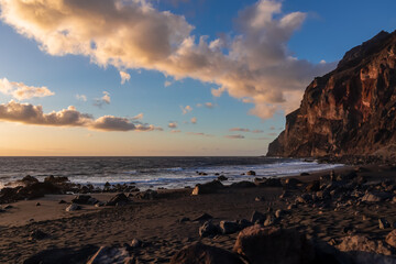 Scenic view during sunset on the volcanic sand beach Playa del Ingles in Valle Gran Rey, La Gomera, Canary Islands, Spain, Europe. Massive cliffs of the La Mercia range. Calm atmosphere at the seaside