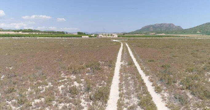 Pista atraviesa salina seca des&eacute;rtica con casa al fondo