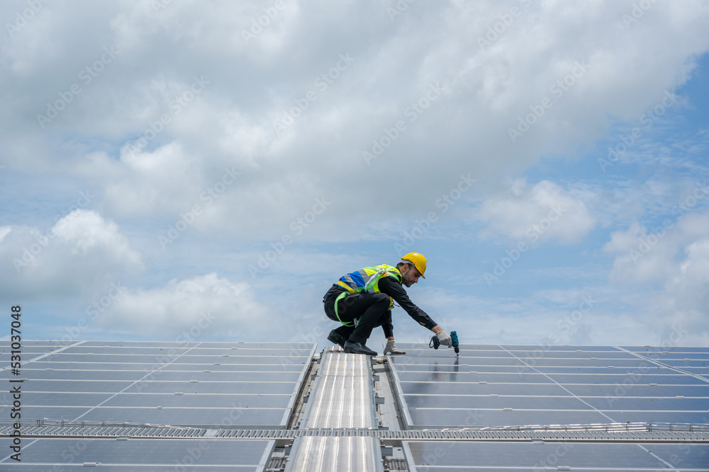 Poster professional worker using drill installing solar panels on the roof of a factory,alternative energy 