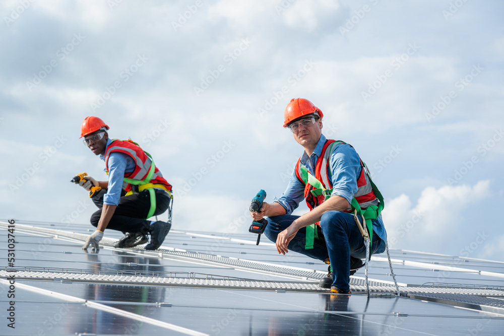 Poster technician wearing safety harness belt during installing the solar panels on roof structure of build