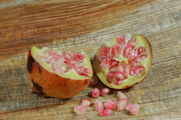 An open section of a pomegranate fruit exposing the ripe red seeds within.