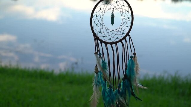 Early morning breeze moves the dream catcher over water and under the sky