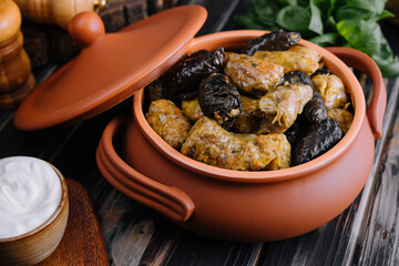 Dolma with meat, rice in grape leaves in a clay pot