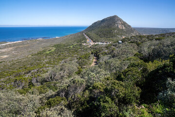 Naklejka premium A spectacular scenic view from the old Cape Point lighthouse of dense green foliage and land-forms with the blue sea on the horizon.