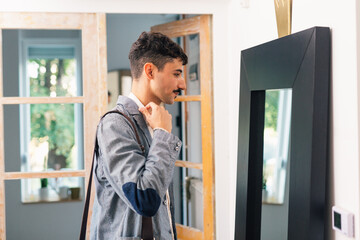 young businessman prepares for work, standing in front of mirror in his home