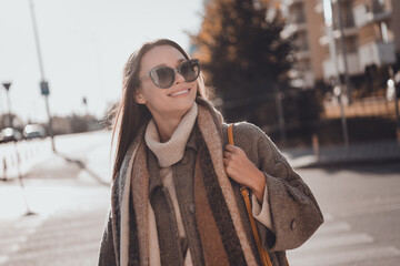 Photo of dreamy positive woman wear grey coat dark glasses walking shopping center enjoying morning...