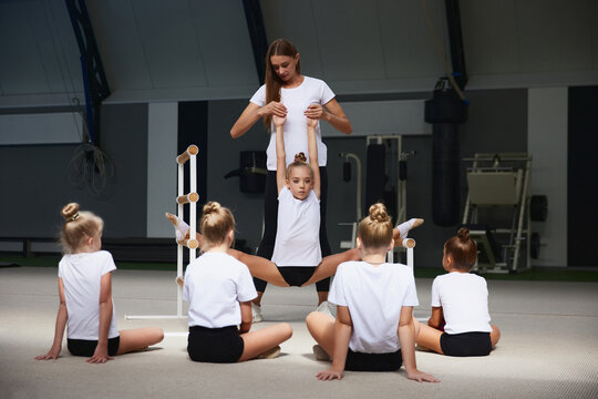 Coaching. Beginner gymnastics athletes doing exercises with gymnastics equipment at sports gym, indoors. Concept of sport, studying, art, education