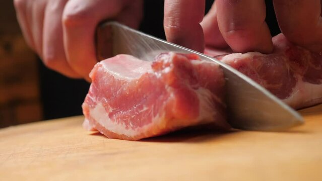 Divides raw pork ribs with a knife on a wooden board. Cutting pork ribs. Preparation food concept